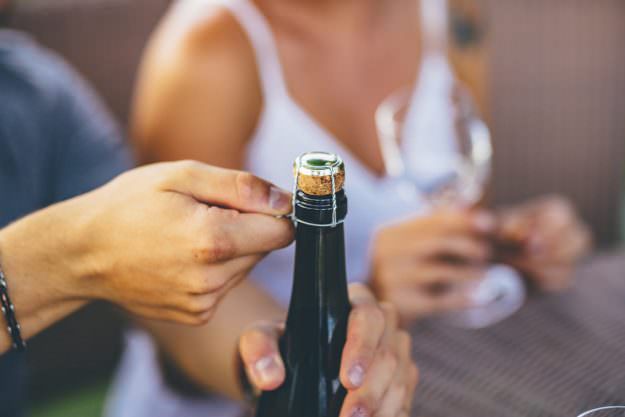 romantic couple opening a wine bottle in an outdoor party organic sparkling wine