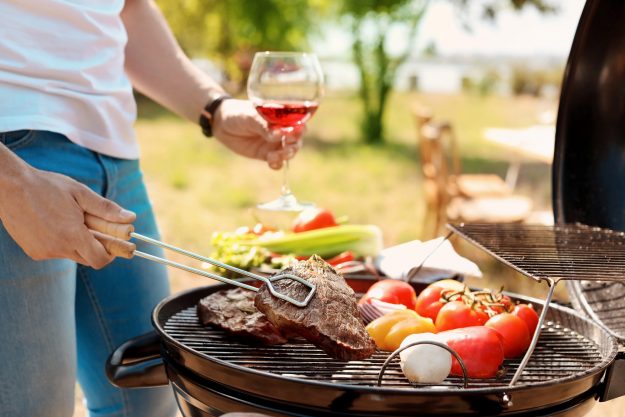 Man cooking meat and vegetables on barbecue grill outdoors Organic Wines for Tallgating